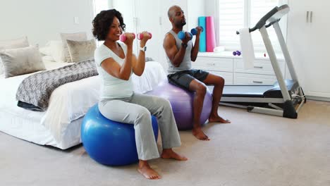 Couple-exercising-with-dumbbells-on-exercise-ball-4k