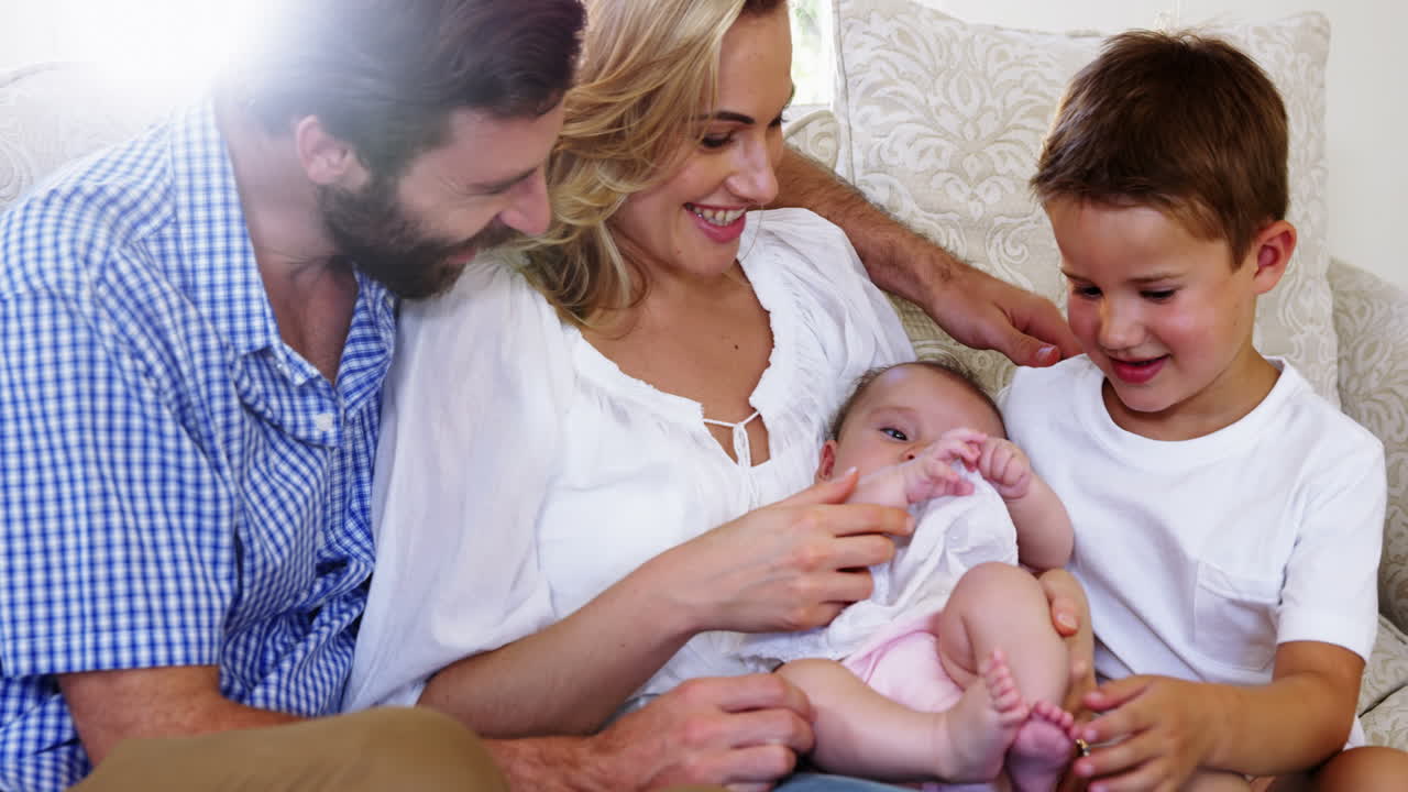 schöne familie sitzt auf einem sofa und hält ein baby
