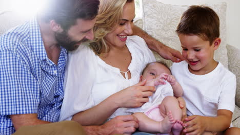 cute-family-sitting-on-a-sofa-and-holding-a-baby