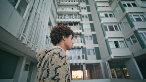 relaxed man strolling buildings in twilight closeup. multiracial guy walking