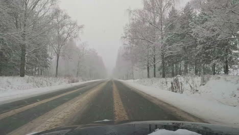 pov driving along cold winter empty road with snow falling