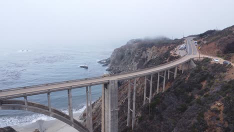 a drone shot passing over a bridge next to the coast.