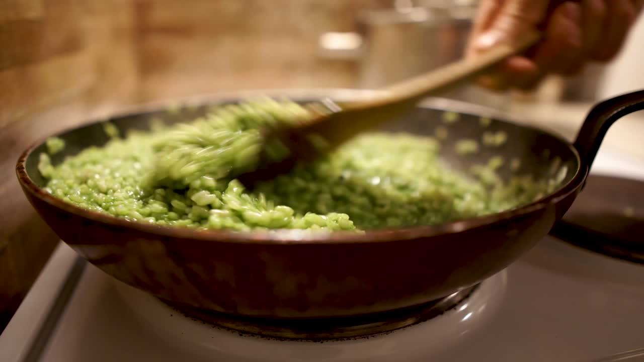 Stirring green spinach risotto with a wooden spoon while hot steam rises into the air, STILL, 4k