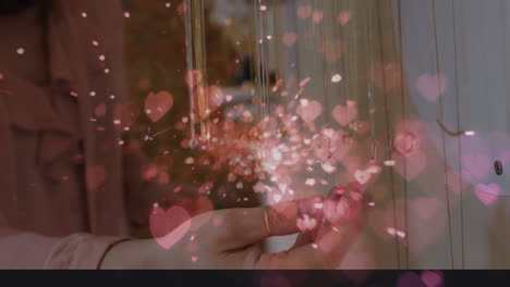 animación de corazones sobre una mujer caucásica tocando un collar