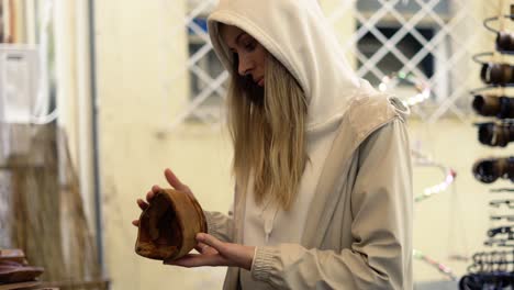 tourist woman in hood shopping at city street bazaar, looking wooden handcraft items