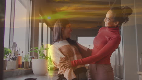 two women smiling and embracing in kitchen with sunset animation overlay