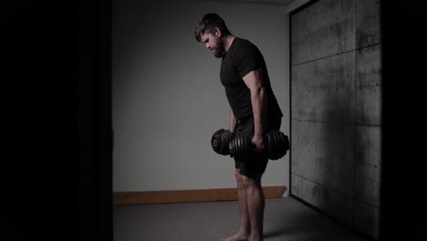 mancuerna doblada sobre la fila, iluminación cinematográfica, hombre blanco vestido con ropa de gimnasio negra