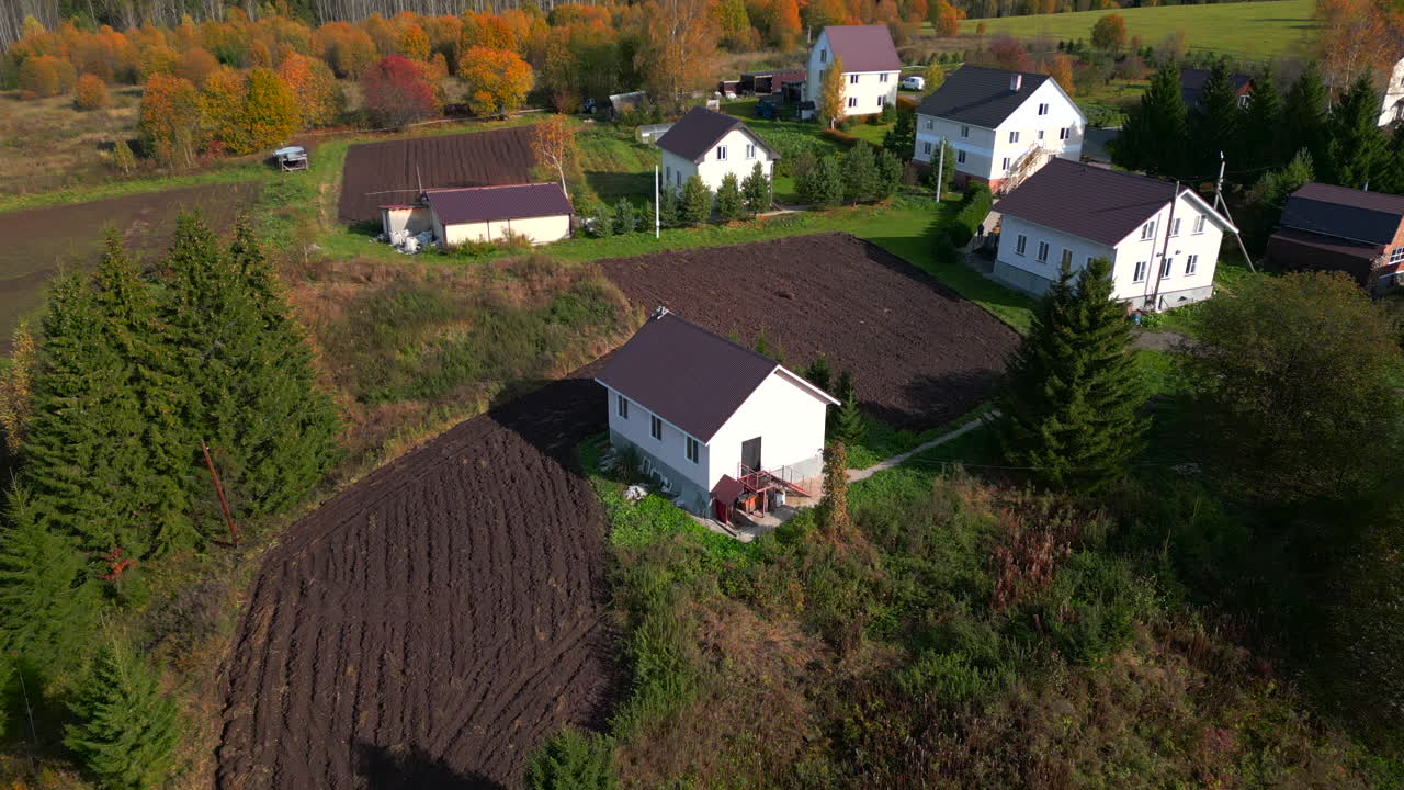Luftfoto af Ensomt Sommerhus ved Pløjet Mark, Omkranset af Stedsegrønne Planter og Krat, Drone-Nærbillede Afslører. Klip