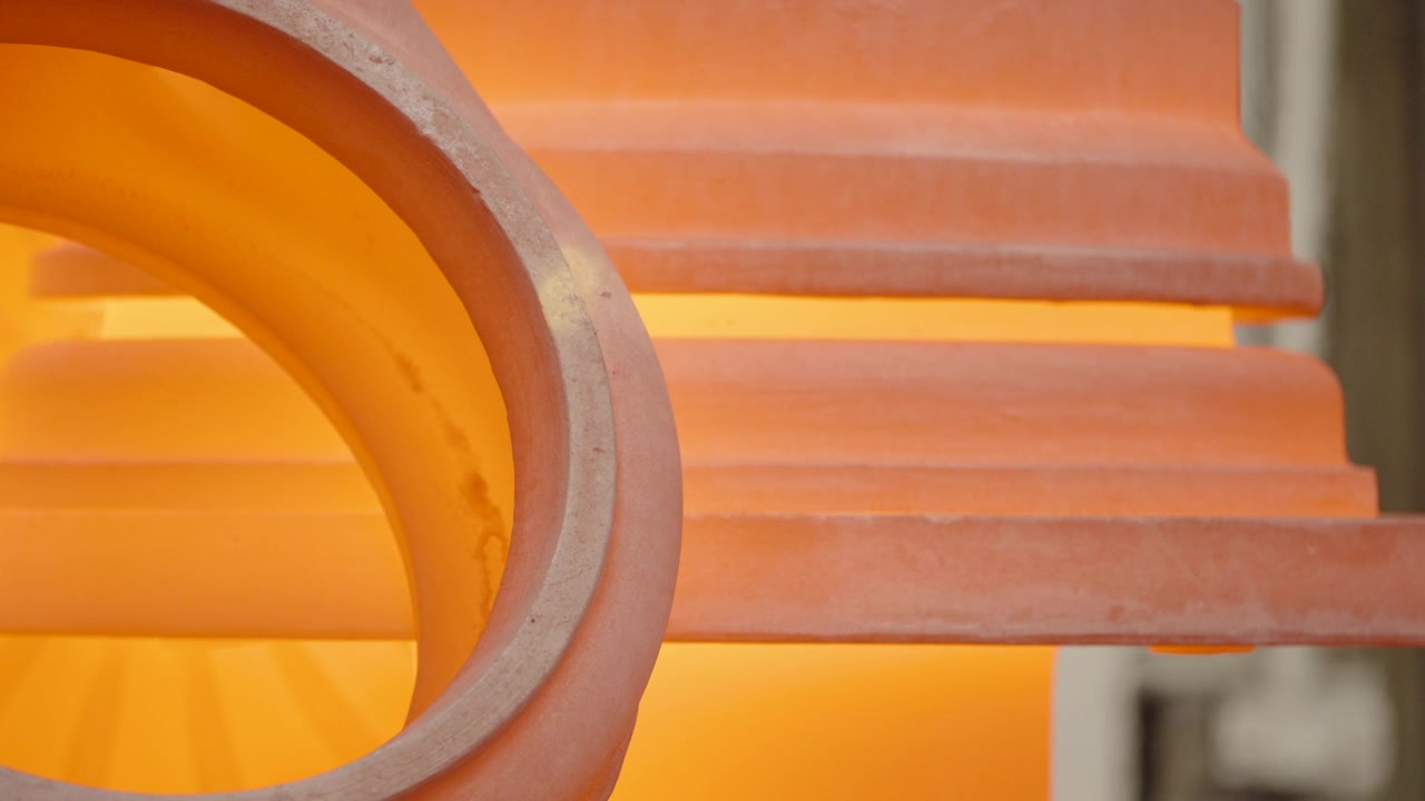 Curved industrial casting molds glow orange from internal furnace light in a tight abstract composition.