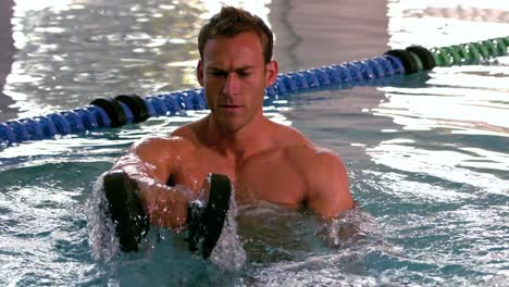 muscular man working out with foam dumbbells in the pool