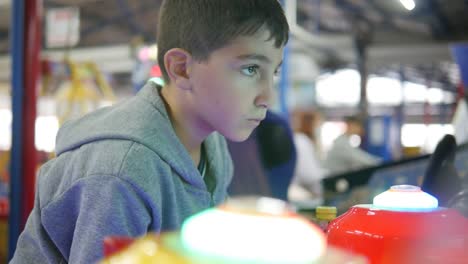 a boy concentrating hard while playing at the arcade