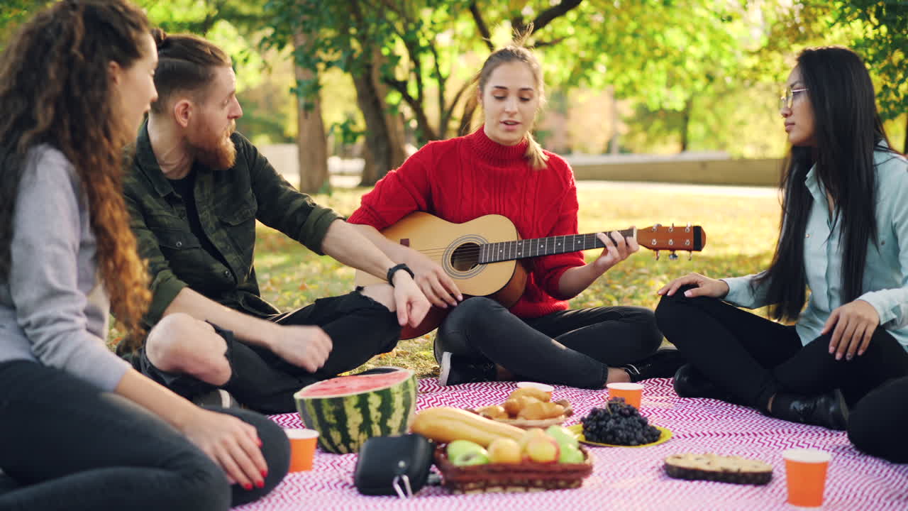 Friends enjoying a picnic in the park while playing music