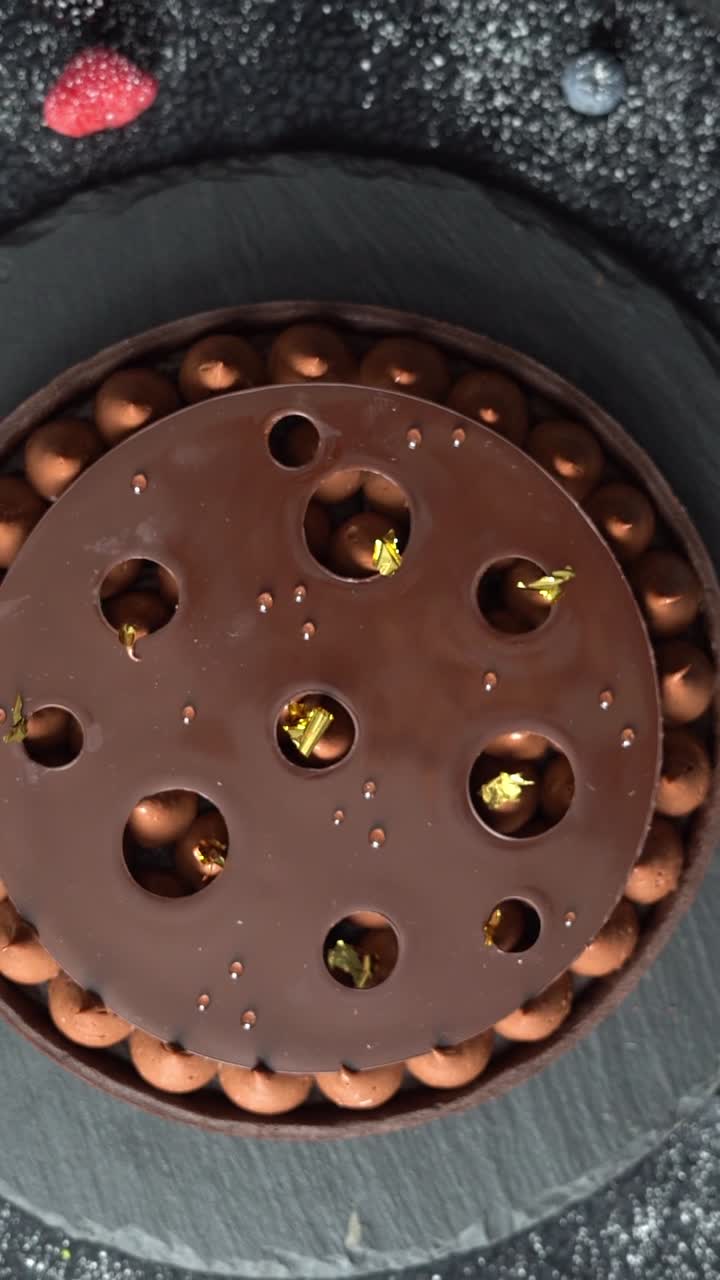 Un chef puso un papel dorado en un pastel de chocolate, primer plano, plano detalle