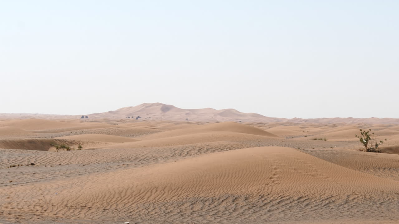 paisaje desértico arenoso con dunas de arena distantes, soleado