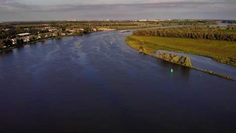 aerial view of fps waal cargo container vessel manoeuvring on river bend on oude maas in the distance