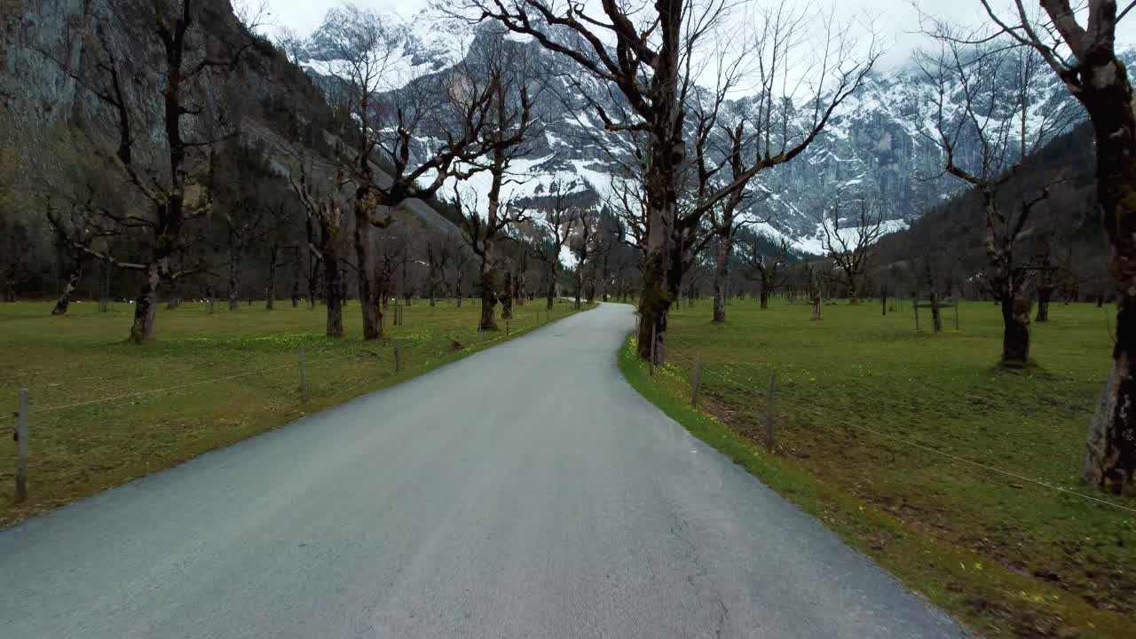 ahornboden austria 바이에른 주 티롤에 있는 목가적인 알프스 산맥의 도로를 따라 낮은 공중 드론 비행, 멀리 오래된 단풍나무와 빙하 눈 산봉우리가 있는 독일 근처