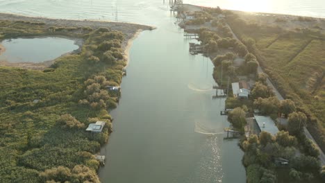 Toma-Aérea-De-Las-Cabañas-De-Pesca-En-El-Río-Que-Desemboca-En-El-Mar-Adriático,-Lido-Di-Dante,-Fiumi-Uniti,-Ravenna-Cerca-Del-Valle-De-Comacchio