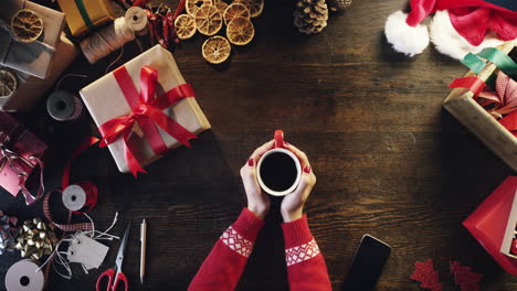 Vista-Superior-Manos-De-Mujer-Sosteniendo-Una-Taza-De-Café-Roja-Regalos-De-Navidad-Mesa-De-Compras-En-Línea-Desde-Arriba---Dragón-épico-Rojo