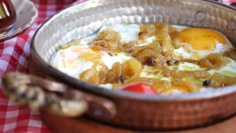 fried eggs with onions in a copper pan