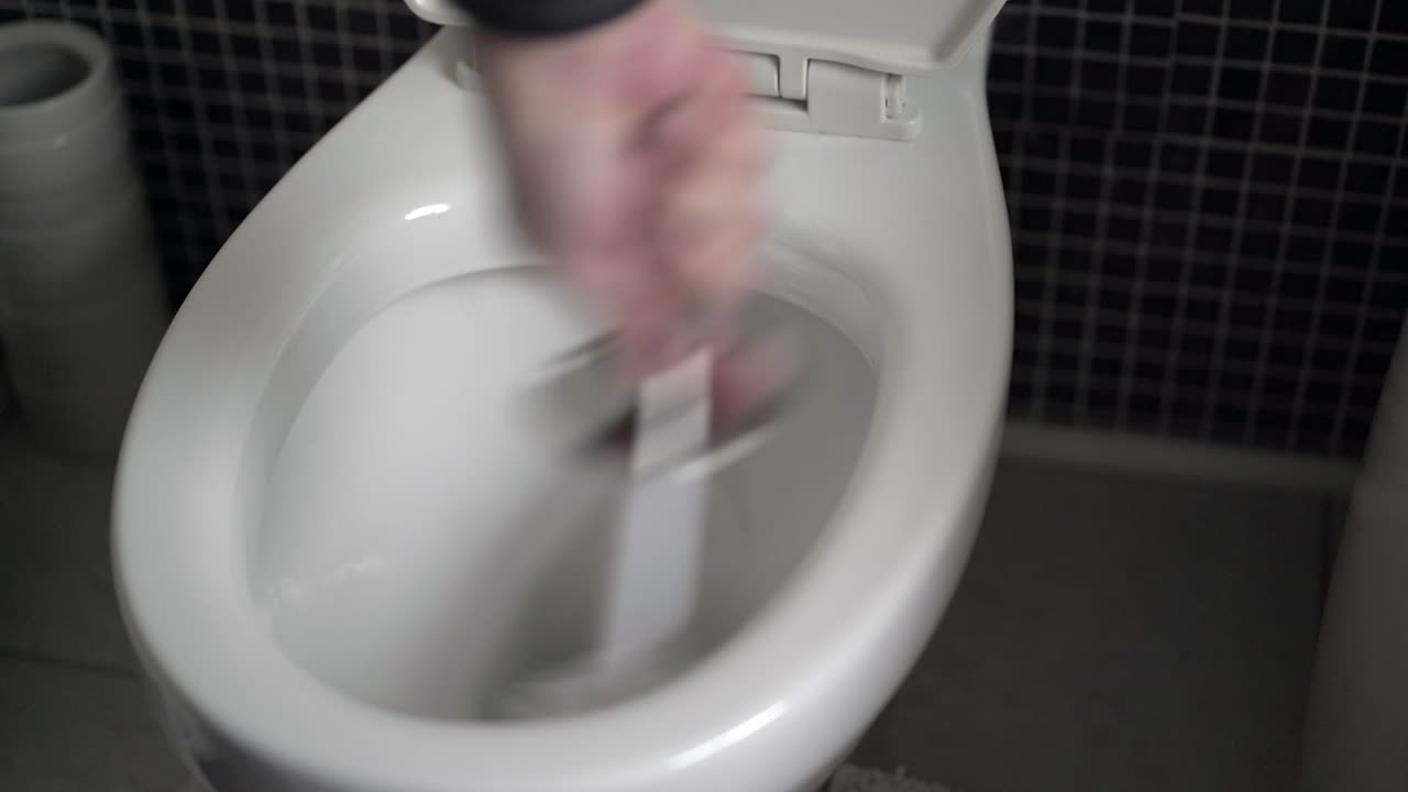 mano de hombre fregando el inodoro blanco con un cepillo de baño
