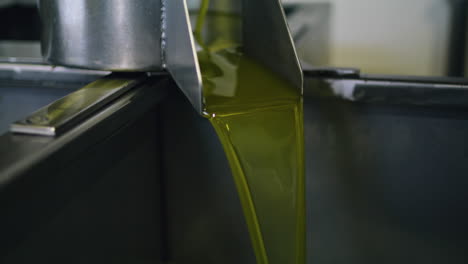 unfiltered oil pouring container at factory closeup. olive flowing vertically