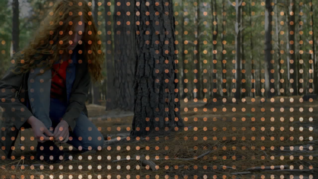 Woman kneeling examining pine cone in pine forest, showing science data with orange dot grid