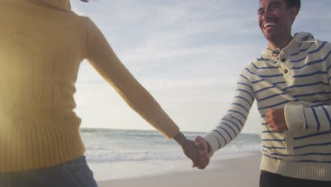 happy hispanic couple running and having fun on beach