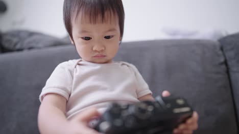 portrait focus on little cute baby girl intently playing with camera screen and buttons