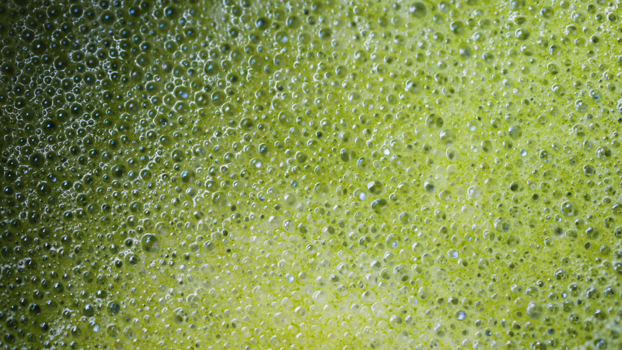 Close up of a smooth matcha latte with vibrant green foam in a white cup
