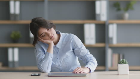 woman leaning on laptop at desk, sleepy