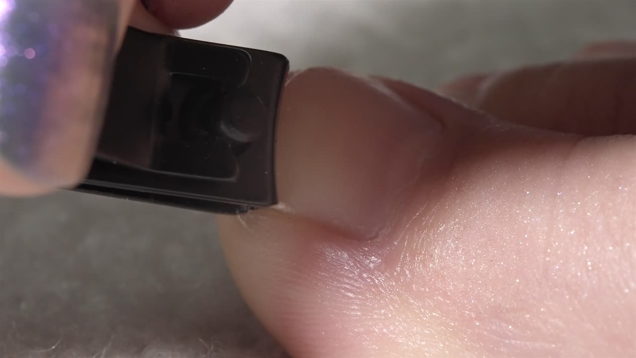 Detailed close-up showing a toenail being cut using a black-colored nail clipper tool