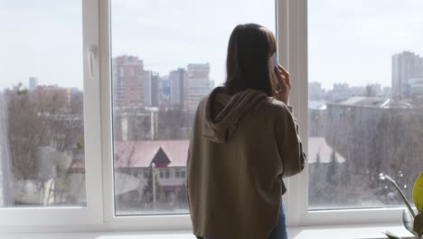 woman at window looking at city view