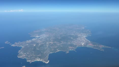 Panoramic-view-of-Ibiza-island,-Spain,-shot-from-a-jet-cabin-while-flying-eastbound-at-3000m-high