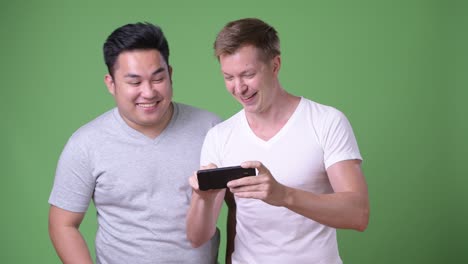 two young multi-ethnic handsome men together against green background