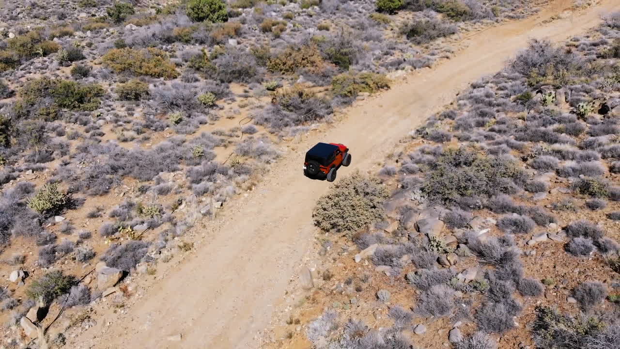antena de vehículo todoterreno naranja conduciendo por un camino de tierra a través de las montañas del desierto - velocidad normal