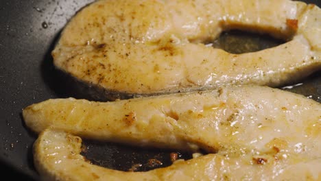 fried salmon with butter on a black pan. loop. seamless clip. healthy menu with low calories.