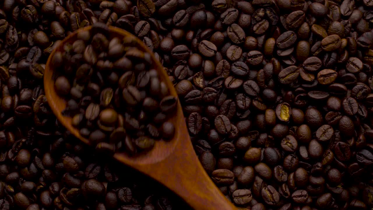 Filmato 4K. 4096x2304P. Chicchi di caffè profumati tostati in padella, con fumo che sale. L'intera composizione ruota lentamente intorno alla telecamera. Mescolare i chicchi di caffè.