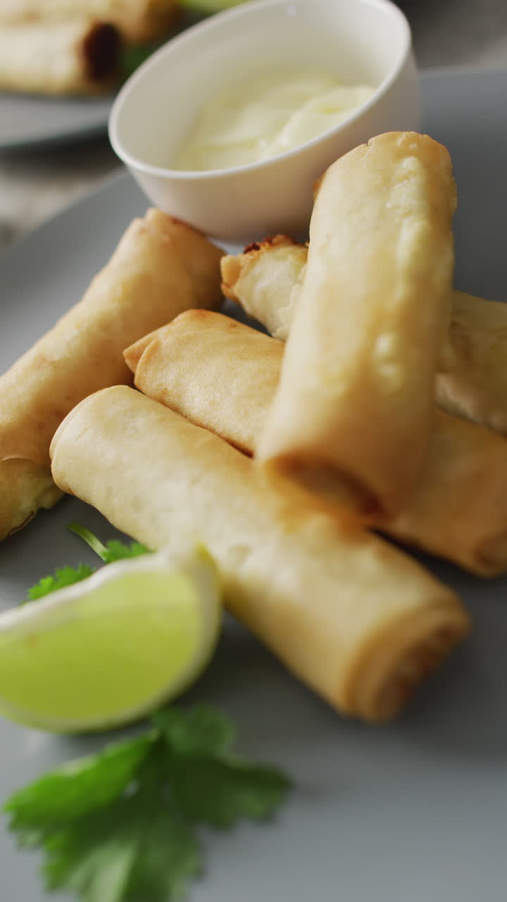 Video vertikal piring berisi lumpia dan saus dengan latar belakang abu-abu