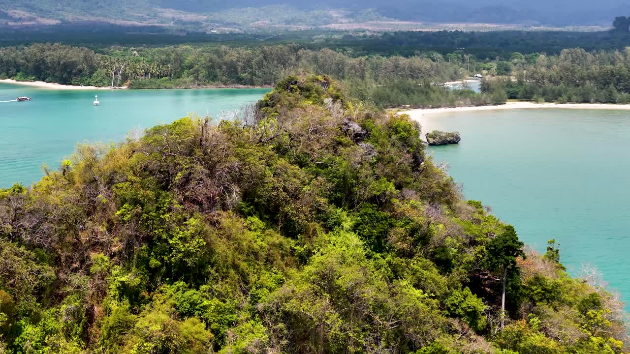 Drone pulls back over lush green limestone islands surrounded by clear turquoise ocean water