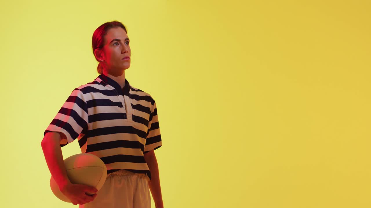 jugadora de rugby caucásica con pelota de rugby sobre iluminación amarilla de neón