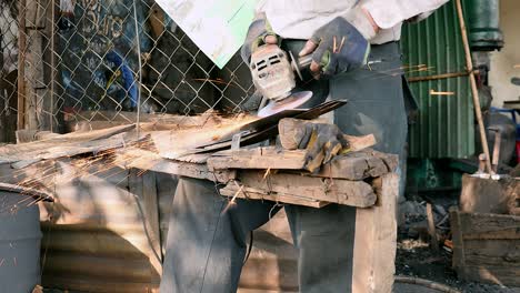 worker sharpening a broad blade with a grinding wheel