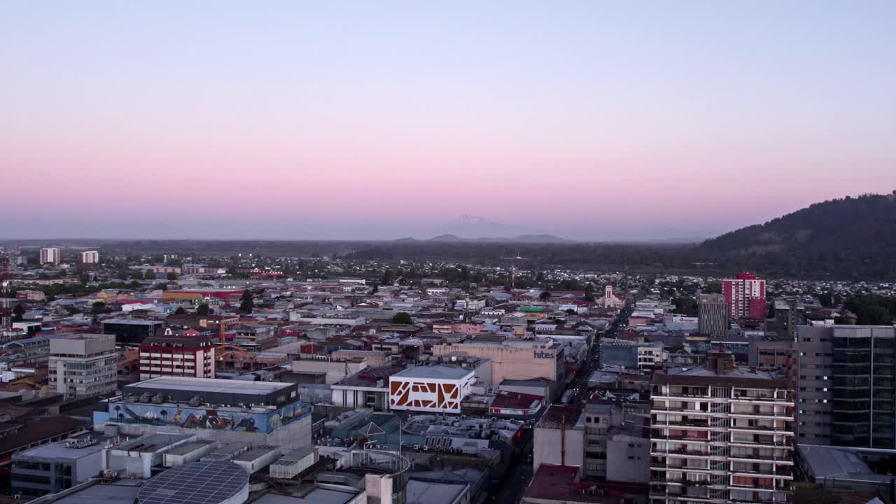 camión de vista aérea dejó el establecimiento de la ciudad de temuco en la hora azul con el volcán llaima en el fondo, toma épica del sur de chile