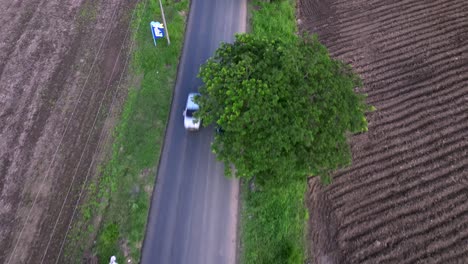 Aerial-shot,-looking-down-following-a-car-on-an-asphalt-road,-near-the-El-Castillo-neighborhood,-in-Valle-del-Cauca