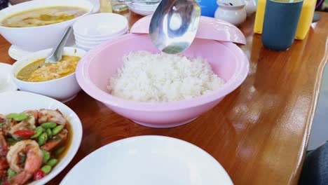 person serving rice into bowls at a table