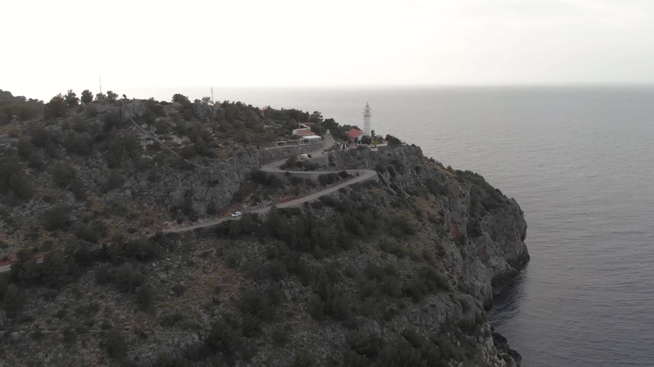 Aerial, drone shot panning around the Far des Cap Gros lighthouse, near Port de Sóller, cloudy evening, in Mallorca, Spain