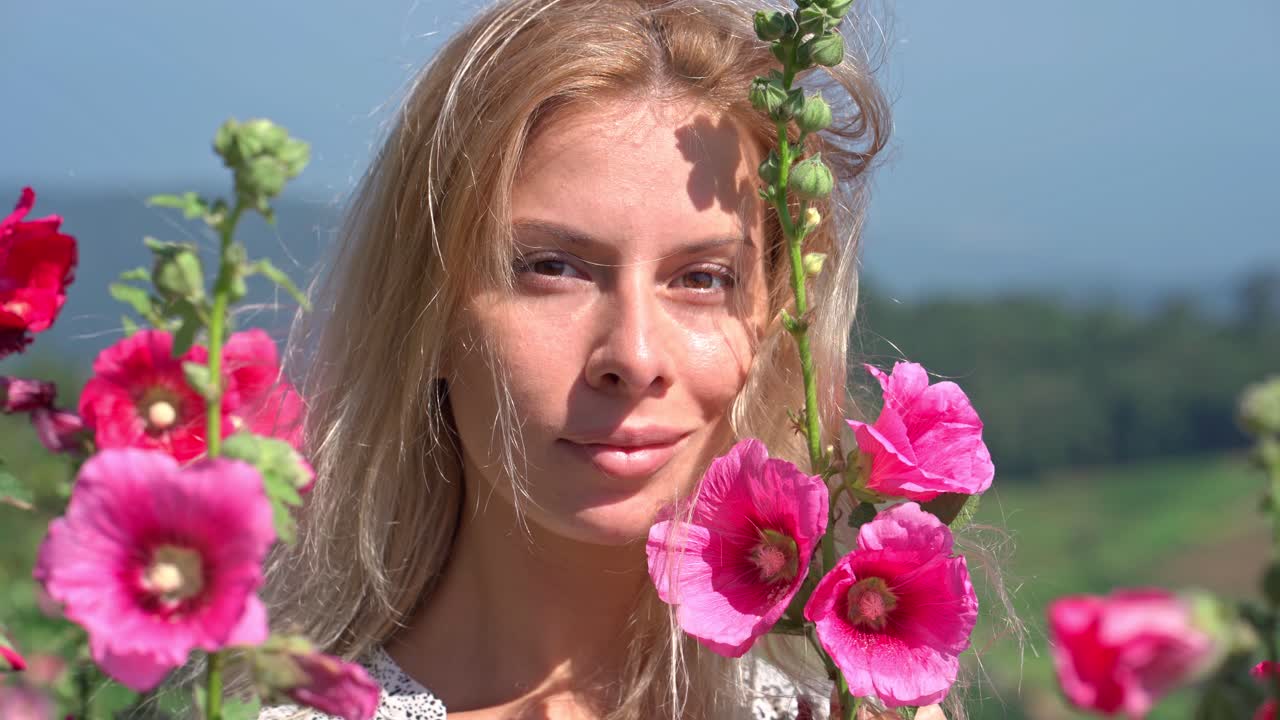 Bella giovane donna che sorride tra fiori rosa all'aperto