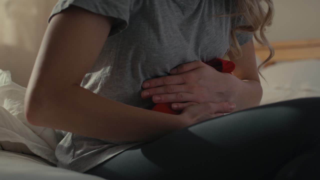 Caucasian woman with pain of belly sitting on the bed at home.