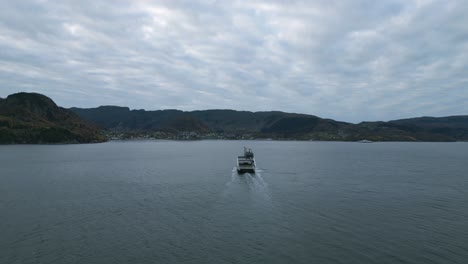 Eine-Fähre-überquert-Ruhige-Gewässer-In-Der-Nähe-Von-Nesvik-Mit-Hjelmeland-Im-Hintergrund,-Bewölkter-Himmel,-Luftaufnahme