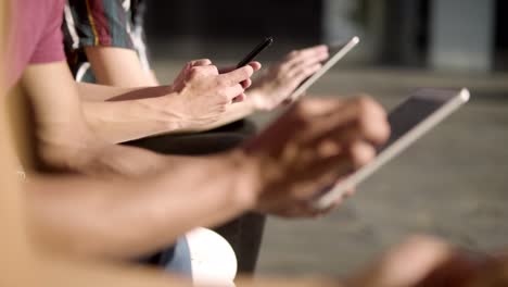 people sitting on wooden bench and using digital devices