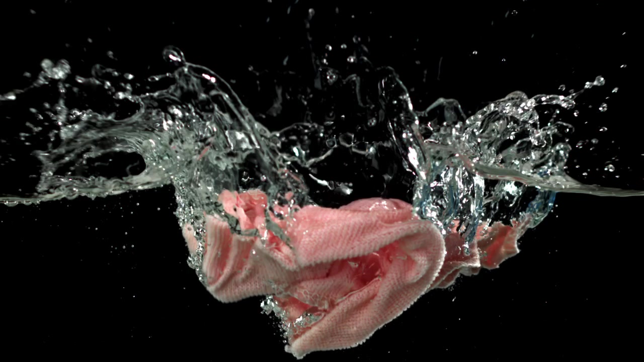 Rosa stoff som faller ned i vann i sakte film